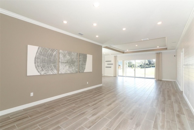 spare room featuring a raised ceiling, light hardwood / wood-style flooring, and ornamental molding