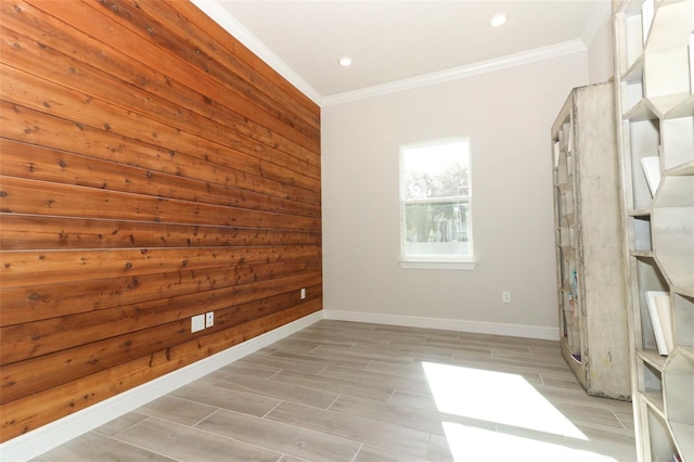 spare room with wood walls, crown molding, and light wood-type flooring