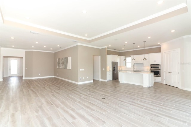 unfurnished living room with light hardwood / wood-style flooring, a wealth of natural light, ornamental molding, and sink