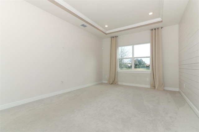 carpeted empty room featuring a raised ceiling and crown molding