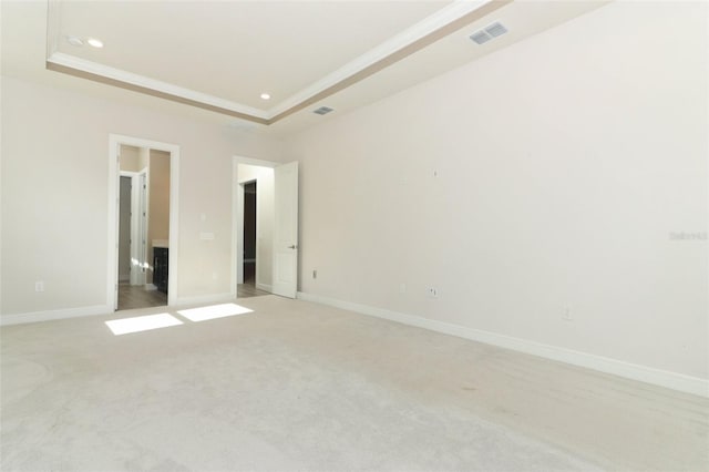 unfurnished room featuring a tray ceiling, crown molding, and light colored carpet