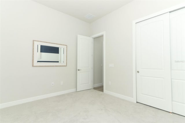 unfurnished bedroom with light carpet and a closet