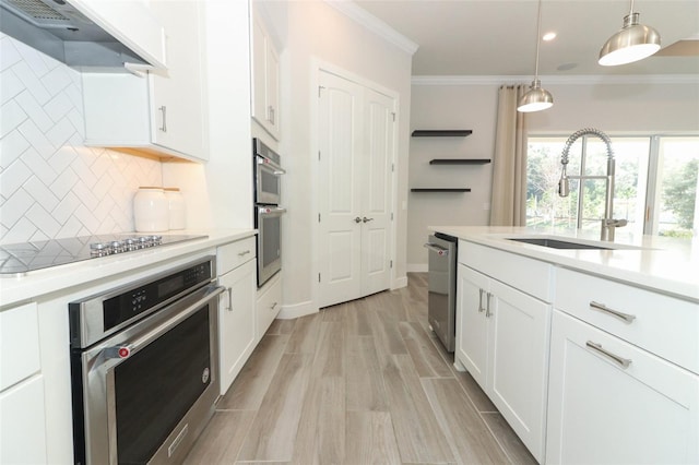 kitchen featuring white cabinets, hanging light fixtures, sink, decorative backsplash, and range hood