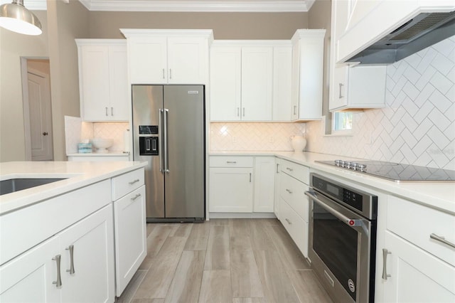 kitchen featuring white cabinetry, hanging light fixtures, stainless steel appliances, premium range hood, and decorative backsplash