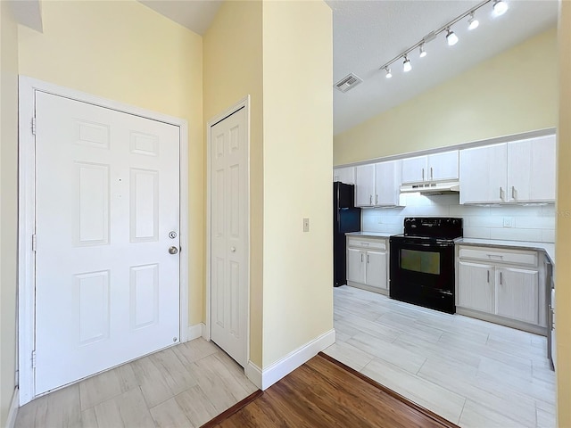 kitchen featuring light wood-type flooring, backsplash, black appliances, white cabinets, and lofted ceiling