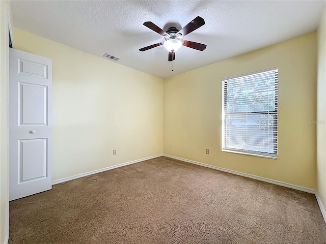 spare room featuring carpet, ceiling fan, and a textured ceiling