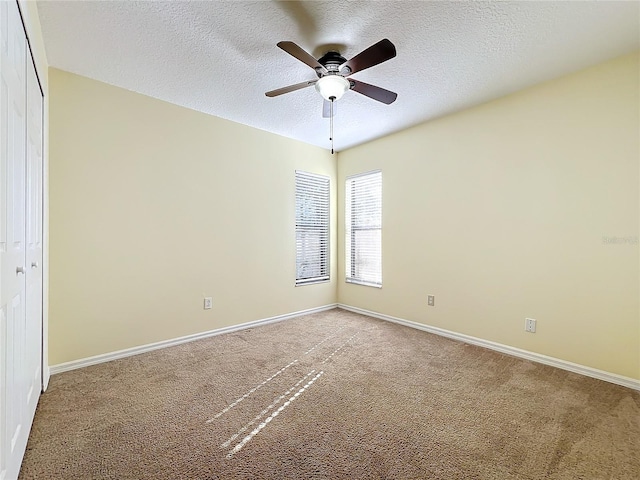 spare room featuring carpet, a textured ceiling, and ceiling fan