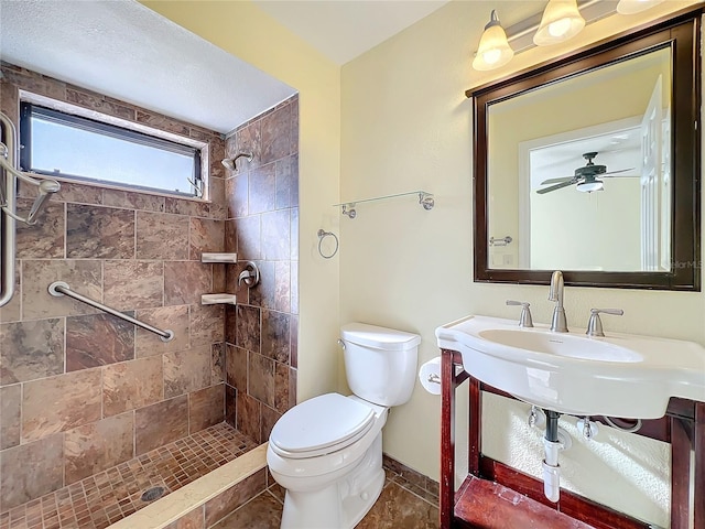 bathroom with tiled shower, tile patterned flooring, toilet, and ceiling fan