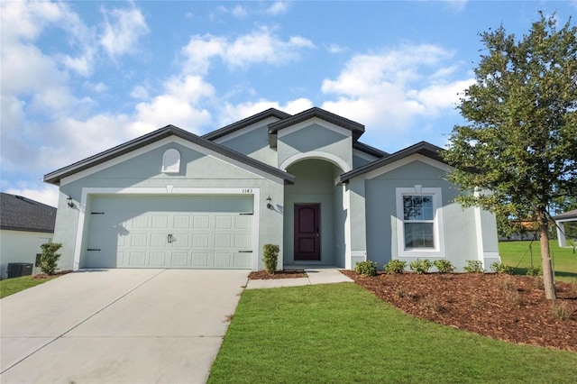 view of front of house with a garage, a front yard, and central AC