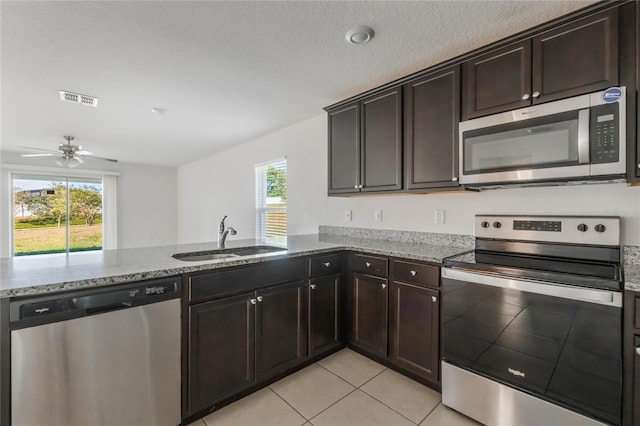 kitchen featuring ceiling fan, kitchen peninsula, sink, light stone countertops, and stainless steel appliances