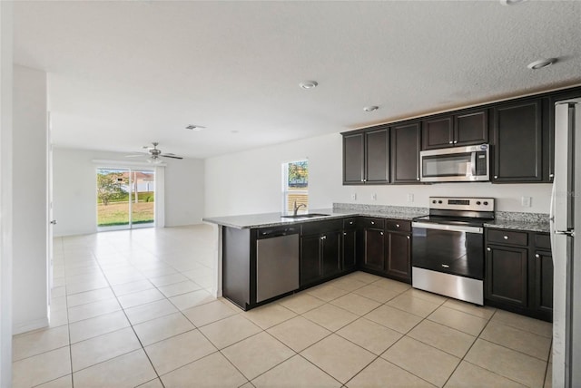 kitchen with light tile patterned floors, appliances with stainless steel finishes, kitchen peninsula, and a healthy amount of sunlight