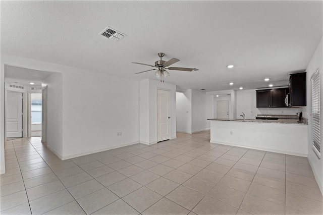 unfurnished living room featuring ceiling fan, light tile patterned flooring, and sink