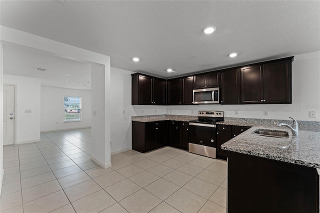 kitchen with light tile patterned flooring, sink, dark brown cabinetry, light stone countertops, and appliances with stainless steel finishes