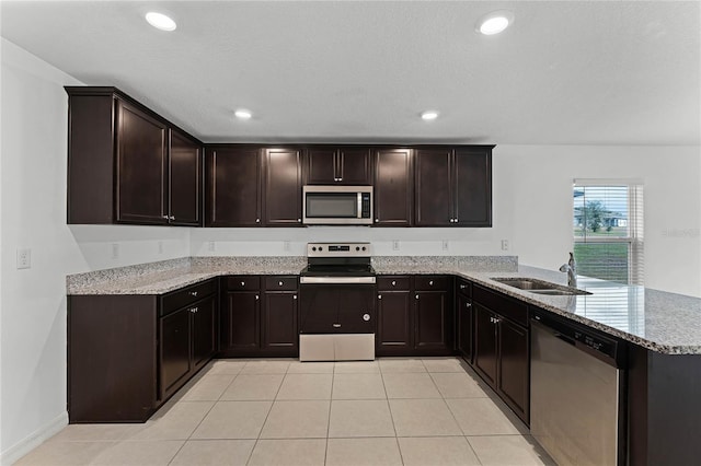 kitchen featuring stainless steel appliances, kitchen peninsula, dark brown cabinetry, and sink