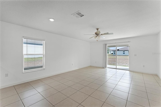 spare room with ceiling fan, light tile patterned flooring, and a textured ceiling