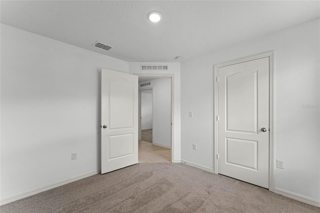 unfurnished bedroom featuring light colored carpet and a textured ceiling