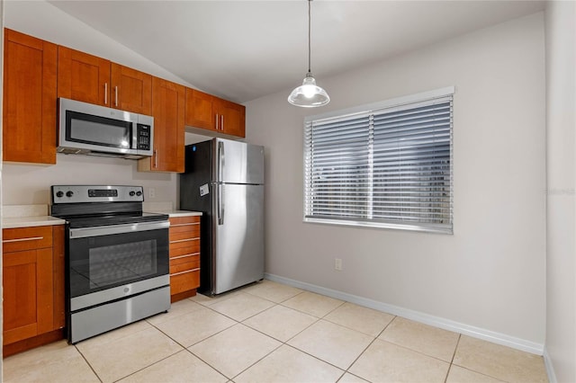 kitchen with hanging light fixtures, vaulted ceiling, appliances with stainless steel finishes, and light tile patterned flooring