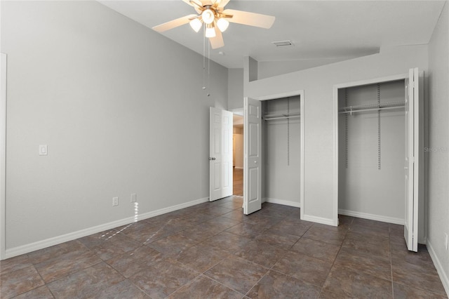 unfurnished bedroom featuring ceiling fan, vaulted ceiling, and multiple closets