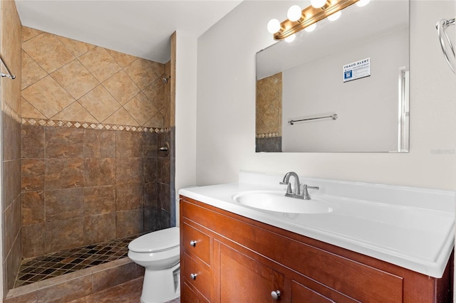 bathroom featuring toilet, vanity, and tiled shower