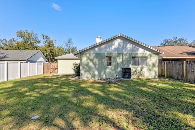 rear view of property featuring central AC unit and a lawn