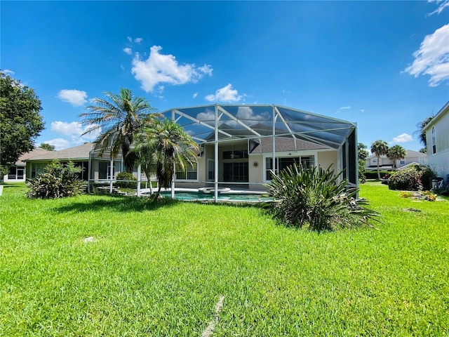 rear view of house with a lanai and a lawn