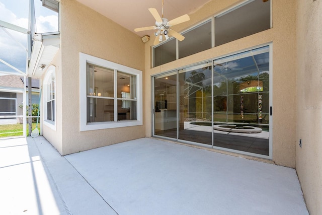 view of patio with ceiling fan and glass enclosure