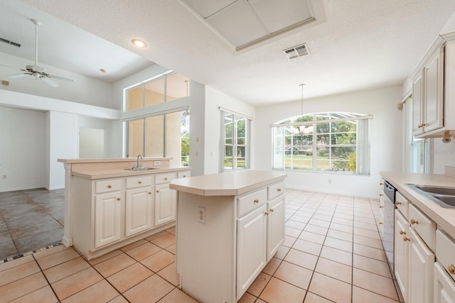 kitchen featuring sink, light tile patterned floors, a center island, white cabinetry, and hanging light fixtures