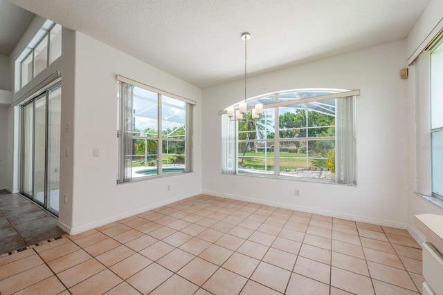 unfurnished dining area with light tile patterned floors, a healthy amount of sunlight, a textured ceiling, and a notable chandelier