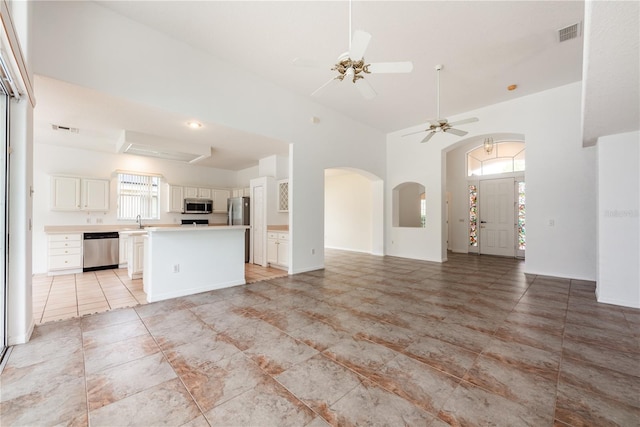 unfurnished living room with a towering ceiling, ceiling fan, and sink