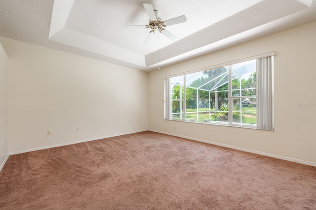 carpeted empty room featuring a tray ceiling, ceiling fan, and a textured ceiling