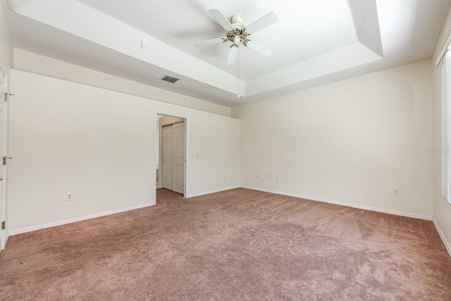 carpeted spare room featuring ceiling fan and a raised ceiling