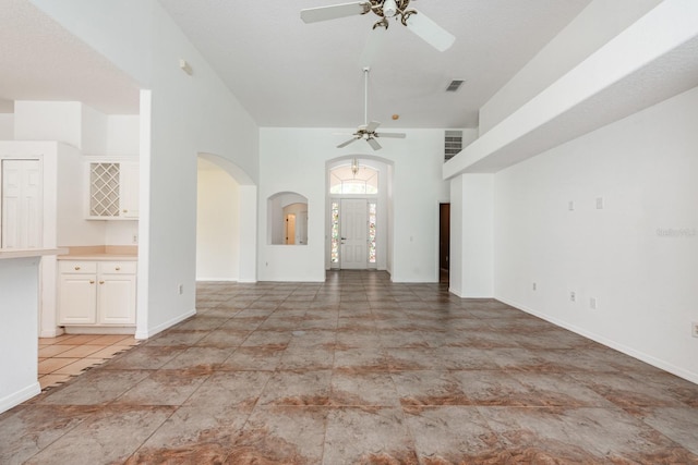 unfurnished living room with ceiling fan and a high ceiling