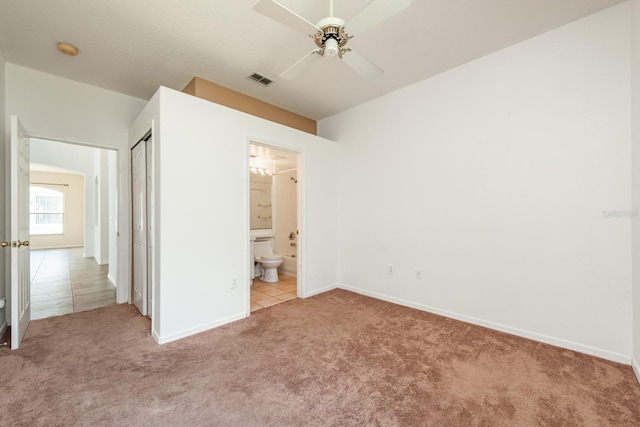 unfurnished bedroom with ceiling fan, light carpet, connected bathroom, and a closet