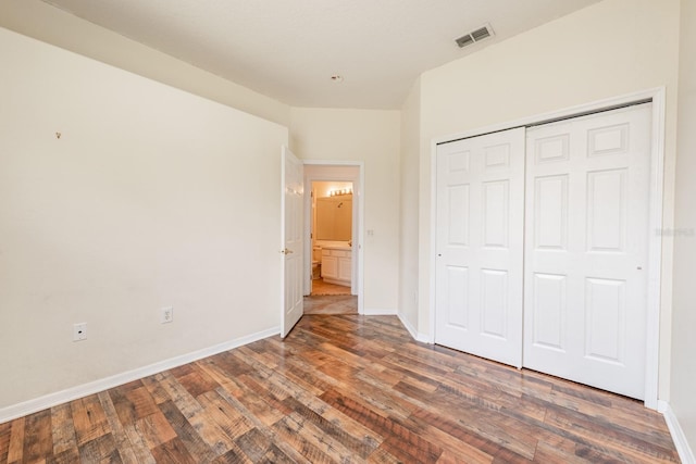 unfurnished bedroom with dark hardwood / wood-style flooring and a closet