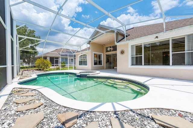 view of swimming pool with glass enclosure, ceiling fan, a patio area, and an in ground hot tub