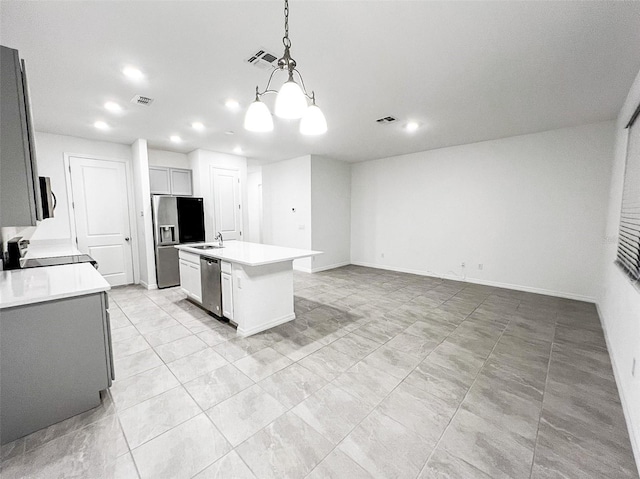 kitchen featuring sink, stainless steel appliances, an inviting chandelier, decorative light fixtures, and a kitchen island with sink