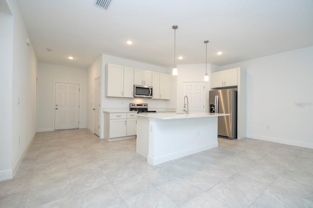 kitchen featuring white cabinets, decorative light fixtures, stainless steel appliances, and an island with sink