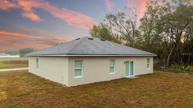 back house at dusk featuring a yard