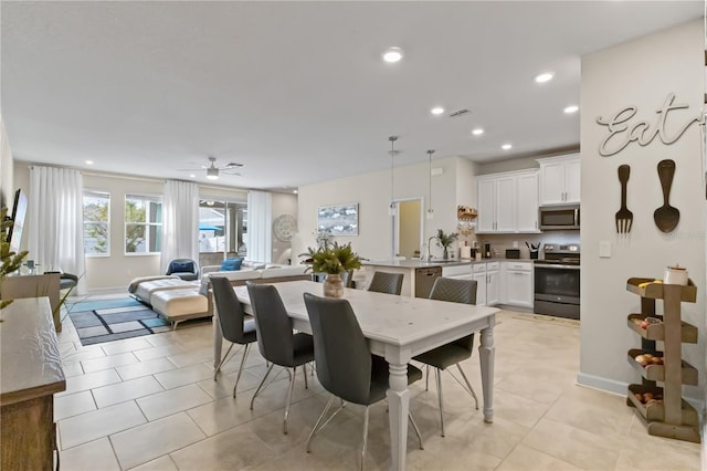 tiled dining space with ceiling fan and sink