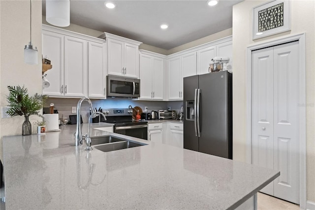 kitchen featuring white cabinets, stainless steel appliances, light stone counters, and sink