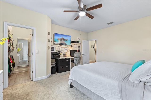 bedroom featuring ceiling fan, ensuite bathroom, and light colored carpet