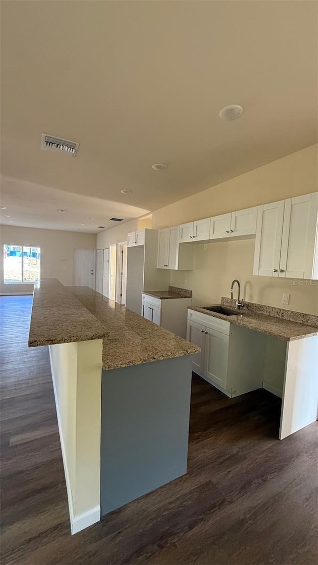 322 N 6th St, Haines City, FL 33844 - kitchen featuring dark wood finished floors, white cabinets, a kitchen island, stone countertops, and recessed lighting