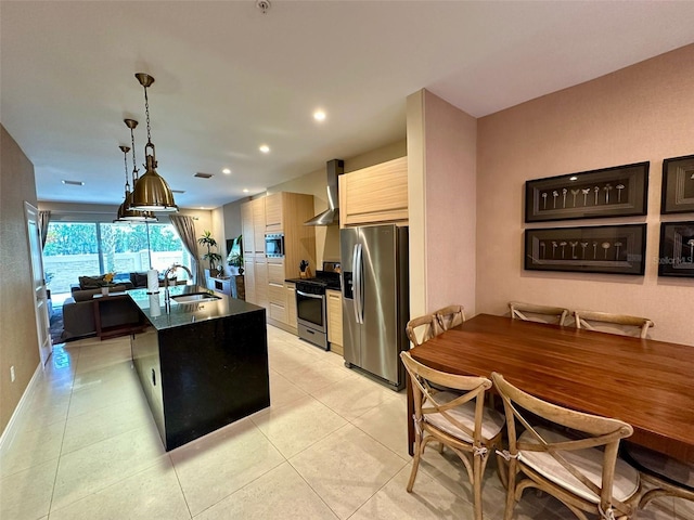 kitchen featuring sink, wall chimney exhaust hood, an island with sink, pendant lighting, and appliances with stainless steel finishes