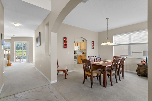 dining space featuring light carpet and a notable chandelier