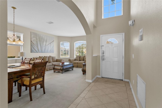 128 Higher Combe Dr, Davenport, FL 33897 - entrance foyer featuring arched walkways, light colored carpet, healthy amount of natural light, a high ceiling, and light tile patterned floors