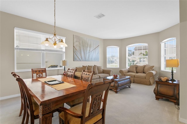 carpeted dining space featuring a notable chandelier and a healthy amount of sunlight