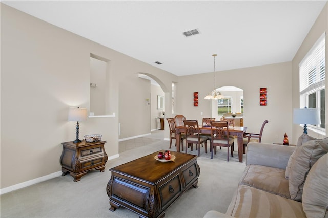 living room with light colored carpet and an inviting chandelier