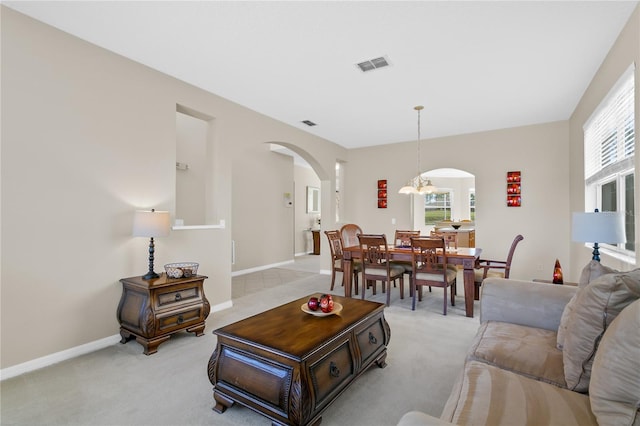128 Higher Combe Dr, Davenport, FL 33897 - living room with arched walkways, light colored carpet, and a chandelier