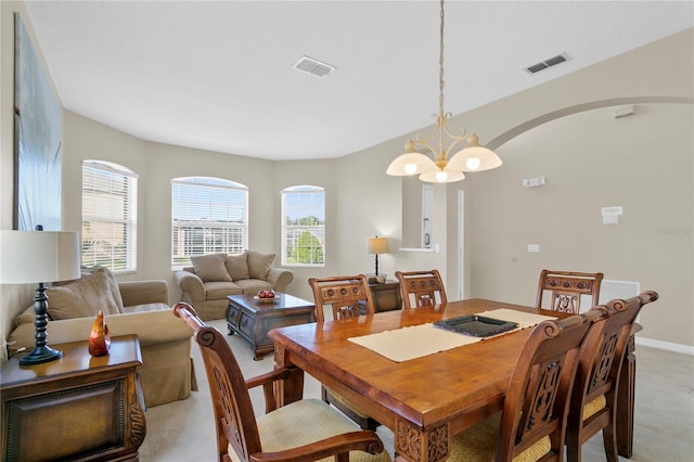 dining space featuring light carpet and a notable chandelier