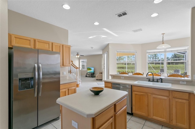 kitchen featuring appliances with stainless steel finishes, ceiling fan, sink, pendant lighting, and a center island